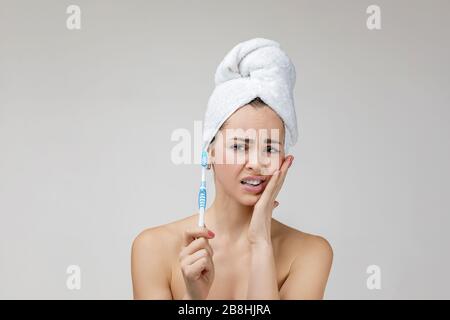 jeune femme caucasienne triste avec brosse dentaire souffrant de douleurs ou de caries dentaires tout en brossant ses dents. fille ayant mal à la dent. Concept de santé et de soins dentaires Banque D'Images