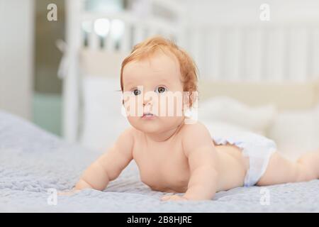 Un bébé souriant est allongé sur un lit dans une chambre. Banque D'Images