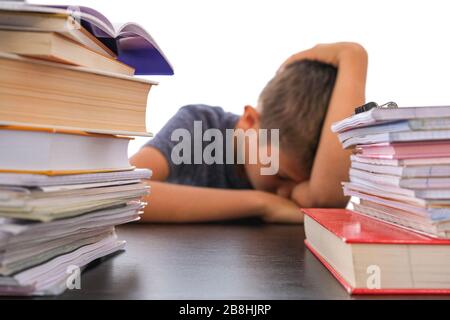Pile de livres pour les devoirs à l'école et fatigué déçu l'école baisse sa tête assise à un bureau Banque D'Images
