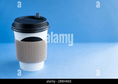 tasse jetable kraft en papier blanc pour café avec couvercle en plastique noir. café à fond bleu. Banque D'Images