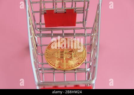 La pièce d'or avec l'image de bitcoin se trouve dans le panier. Banque D'Images