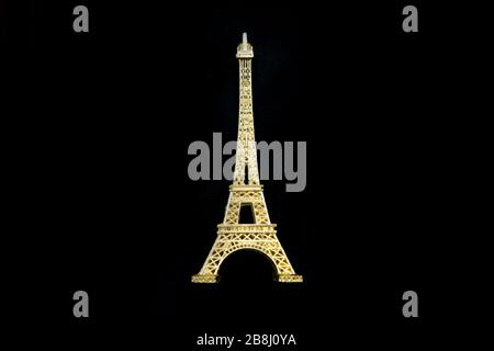 La petite tour Eiffel dorée en souvenir de Paris. Isolé sur un fond noir.