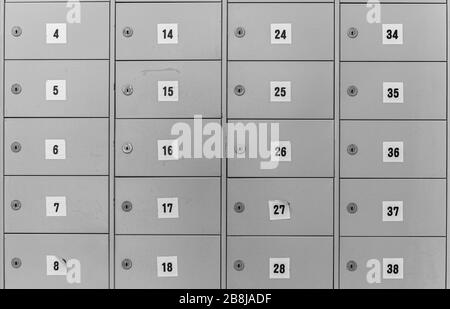 Image abstraite de boîtes métalliques verrouillées numérotées avec portes à charnières, disposées en grille. Banque D'Images