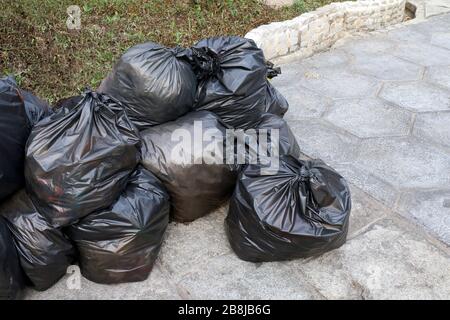 déchets tas de déchets sacs noirs pile plastique sur le sol du parc public, beaucoup de déchets noirs déchets sacs plastique pile Banque D'Images