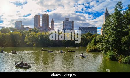 Une belle journée au parc central de New Yorks, les gens font du bateau devant les gratte-ciel en arrière-plan. Banque D'Images