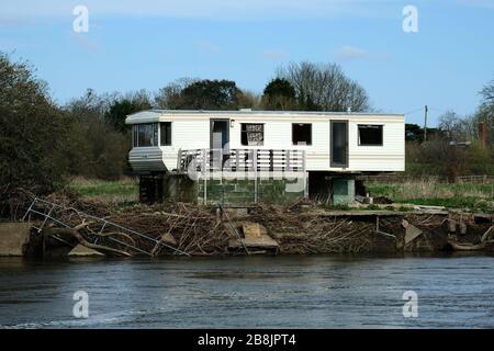 Ancienne caravane de shabby sur une rive de rivière Banque D'Images