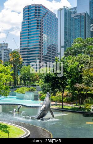 Tours de bureaux et fontaine de sculpture de baleines dans le lac Symphony dans le parc KLCC Kuala Lumpur en Malaisie. Banque D'Images