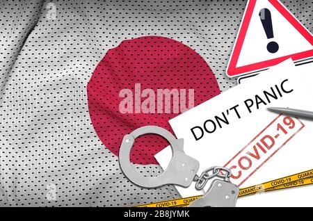 Le drapeau japonais et les menottes de police avec inscription ne paniquent pas sur le livre blanc. Concept de virus coronavirus ou pandémique 2019-nCov Banque D'Images