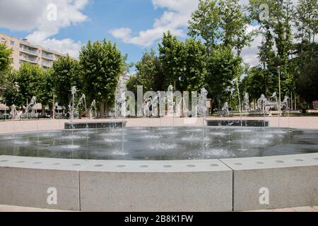 Fontaine européenne avec jets d'eau avec arbres, ciel et nuages Banque D'Images