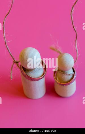 Concept d'amour malheureux. Figurines en bois avec boucles sur le cou sur un fond rose. Mari et femme sont mécontents de l'amour. Photo verticale. Banque D'Images