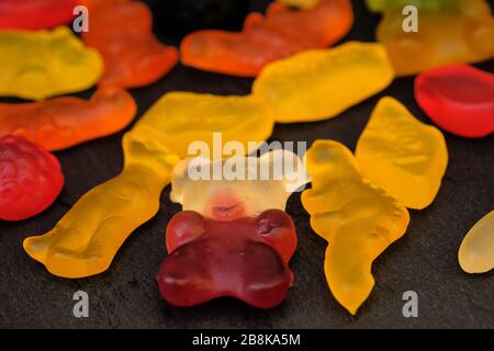 Bonbons en gelée sur fond noir. Bonbons gélifiés sous forme d'animaux de différentes couleurs. Banque D'Images