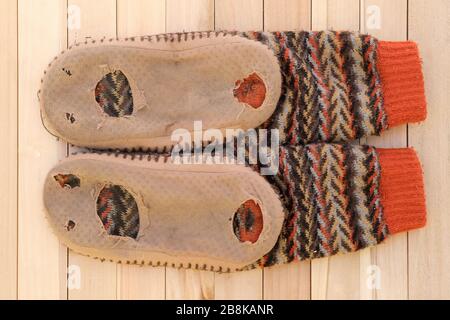 Pantoufles en matières textiles avec trous sur la semelle. Chaussons maison doux et confortables portés. Vieux maison chaussures chaudes. Trous sur le pied, semelle usée. Banque D'Images