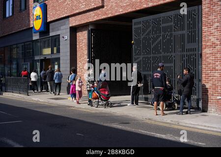 Les gens qui ont une distance de sécurité tout en faisant la queue devant un supermarché pendant la pandémie de Coronavirus, Dublin, irlande. Banque D'Images