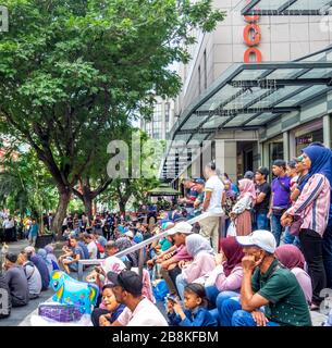 Foule assise sur des marches à regarder un concert gratuit dans la rue bordée d'arbres Jalan Tuanku Abdul Rahman, au centre de Kuala Lumpur en Malaisie. Banque D'Images