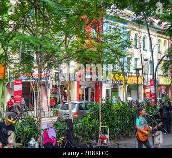 Homme jouant de la guitare et terrasse, boutiques de tissus et de textiles le long de Jalan Tuanku Abdul Rahman Street, au centre de Kuala Lumpur en Malaisie. Banque D'Images