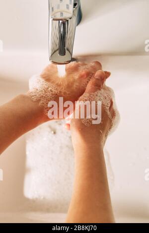 La fille se lave les mains avec du savon pour empêcher le coronavirus. Banque D'Images