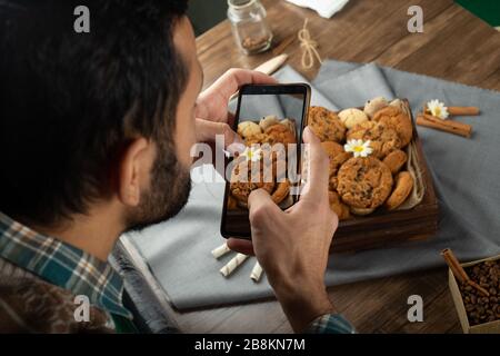 Homme prenant photo du bac à cookies avec son smartphone Banque D'Images