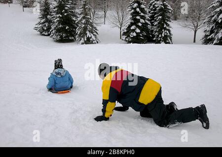 Sport d'hiver toboggan - un père et un fils de santé mûrs jouant au toboggan, hiver, extérieur, mode de vie sain. Banque D'Images