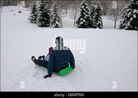 Sport d'hiver toboggan - un père et un fils de santé mûrs jouant au toboggan, hiver, extérieur, mode de vie sain. Banque D'Images