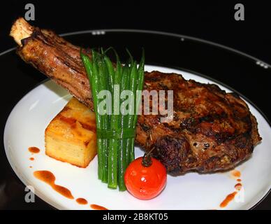 bifteck grillé de bœuf angus avec pomme de terre, haricots verts et tomate dans une assiette blanche et noire Banque D'Images
