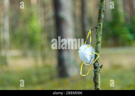 Un masque blanc se bloque sur une branche d'arbre dans une forêt - closeup. En raison d'un masque insuffisant pendant la crise de Covid-19. Quarantaine du virus Corona. Banque D'Images