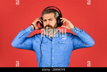 Homme écoutant de la musique avec son casque. Homme barbu hipster dans le casque. Écouter de la musique. Il est temps de se détendre. Les hippers brutaux portent des écouteurs. Chantent et dansent. Profiter de sa musique préférée. Banque D'Images