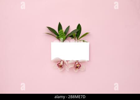 disposition faite de feuilles vertes et de fleurs d'orchidées sur fond rose pastel. Concept de nature tropicale. Mise à plat. Espace vide pour le texte. Maquette avec espace de copie. Banque D'Images