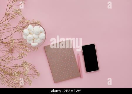 fleurs de gypsophila plat, téléphone mobile et un journal sur fond rose, vue du dessus. espace vide pour le texte. Banque D'Images