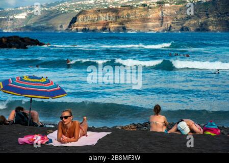 Touristes aux falaises de los gigantes plage de sable noir volcanique à Puerto de la Cruz, île de Tenerife, îles Canaries, Espagne Banque D'Images