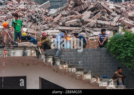 Chongqing, Chine - 9 mai 2010 : centre-ville, à la sortie de la place des peuples. L'équipe de démolition prend une pause déjeuner sur la pile de gravats en pierre. Banque D'Images