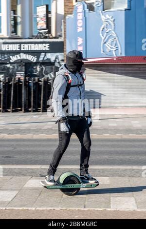 Southend on Sea, Essex, Royaume-Uni. 22 mars 2020. Homme avec masque facial sur une roue, planche à roulettes auto-équilibrée. Future Motion Onewheel XR. Planche à roulettes à une roue Banque D'Images