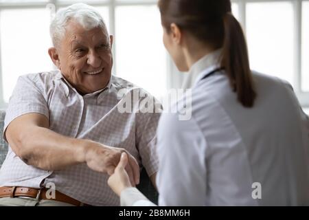 Infirmière en uniforme parlant pendant la visite de jour à un patient âgé Banque D'Images