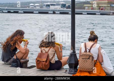 Istanbul, Turquie- Août 04 2019: Vue arrière de trois filles mangeant du maïs bouilli près de la mer, Banque D'Images