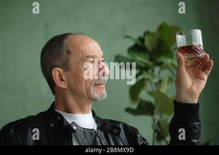 L'homme senior avec barbe et moustache est muni d'un verre de brandy ou de whisky. Alchol degustation, concept dégustation Banque D'Images