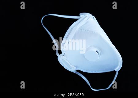 Masque stérile non réutilisable blanc ffp3 avec valve sur fond noir. Concept pour le coronavirus covid-19, maladies respiratoires dues aux allergies et A Banque D'Images