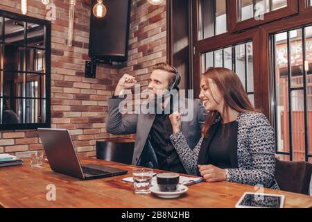 Les gens d'affaires heureux et heureux de célébrer le succès en riant et en faisant des gestes oui tout en regardant le moniteur d'ordinateur portable et en obtenant de grandes nouvelles. Réussite Banque D'Images