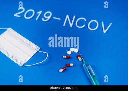 le mot 2019-ncov posé de lettres blanches sur fond bleu classique avec une lumière dramatique. Nouvelle maladie du coronavirus nommée 2019-nCoV . Pilules et masque respiratoire comme concept de coronavirus. Banque D'Images