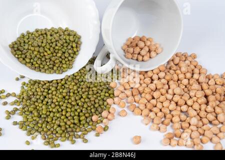 Haricots verts et pois turcs versés à partir de tasses blanches sur la table. Ingrédients asiatiques de plats traditionnels. Banque D'Images