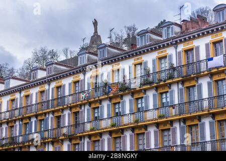 Bâtiment sur Constitucion Plaza dans la ville côtière de San Sebastian située dans la Communauté autonome basque, Espagne, vue avec la statue de Jésus sur le mont Urgull Banque D'Images