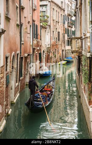 Gondolier naviguant sur les canaux de Venise avec des passagers sous la pluie. Banque D'Images