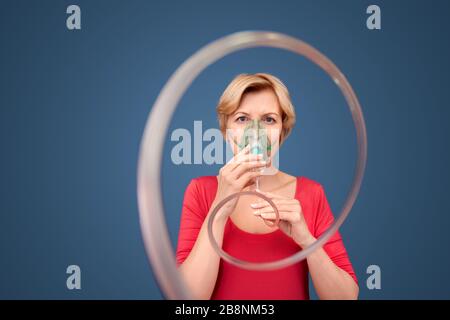 Femme mature avec masque d'oxygène debout en studio Banque D'Images
