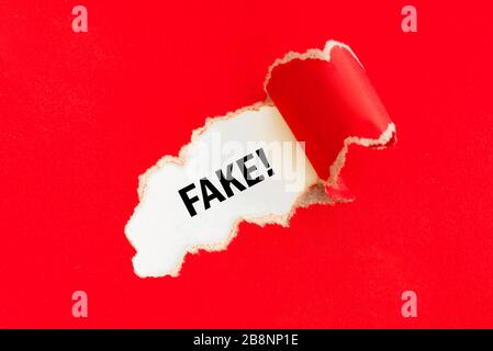 Papier rouge déchiré avec mot faux sur fond blanc. Concept de fausses nouvelles. Banque D'Images