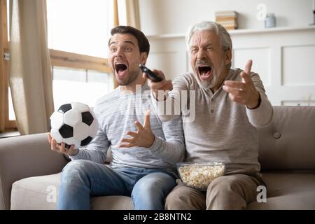 Un jeune homme excité s'amuse à regarder le jeu avec son père Banque D'Images