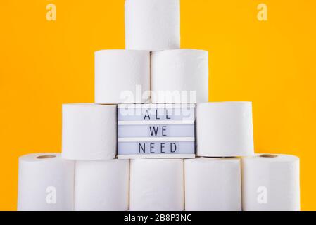 Tour empilée de rouleaux de papier toilette doux, planche allégée avec tout ce dont nous avons besoin message entre les rolles sur fond jaune vif. Le manque de créativité en matière de crise Banque D'Images