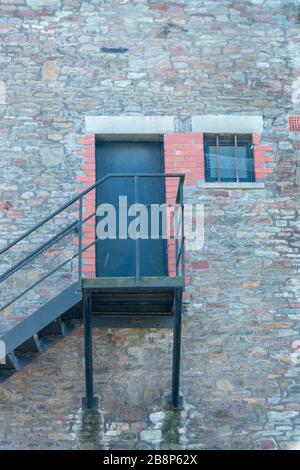 vue rapprochée d'un escalier métallique menant à une porte noire solide sur le côté d'un bâtiment Banque D'Images