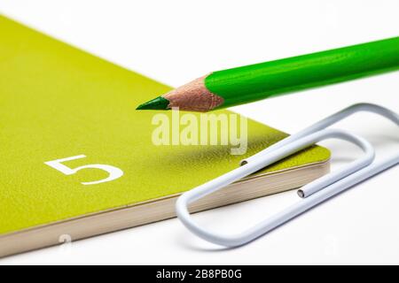 Organisateur pour le mois de mai, crayon vert et trombone blanc sur la table blanche. Banque D'Images