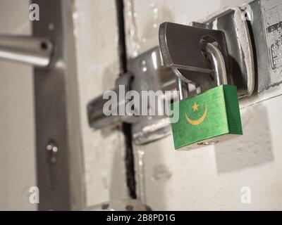 Une porte boulonnée fixée par un cadenas avec le drapeau national de la Mauritanie dessus.(série) Banque D'Images