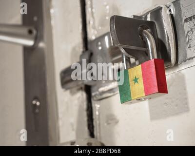 Une porte boulonnée fixée par un cadenas avec le drapeau national du Sénégal.(série) Banque D'Images