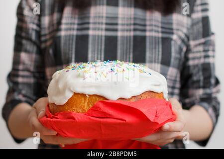 Gâteau de Pâques traditionnel dans les mains des femmes. Pain de Pâques avec crème blanche et décoration colorée sur le dessus. Concept de menu. Banque D'Images