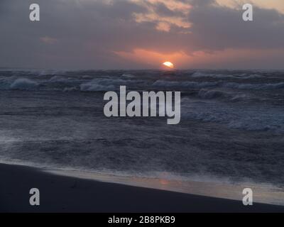 Coucher de soleil sur la mer Baltique, plage vide, vagues sur la mer. Prise de vue par temps venteux. Leba, Pologne. Banque D'Images